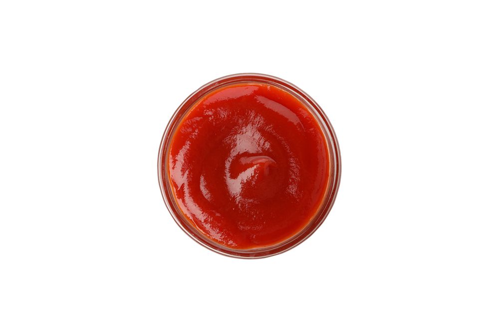 Glass bowl with tomato sauce isolated on neutral background
