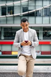 Man using smartphone leaning against wall