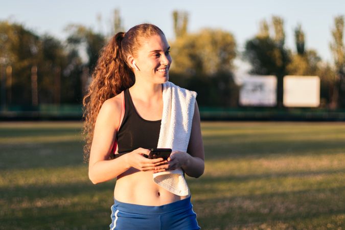 An athletic woman resting with her smartphone after running.