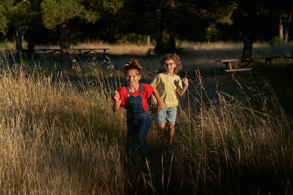 Cheerful siblings running in nature