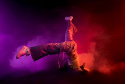 Young woman break dancing in colorful smoke