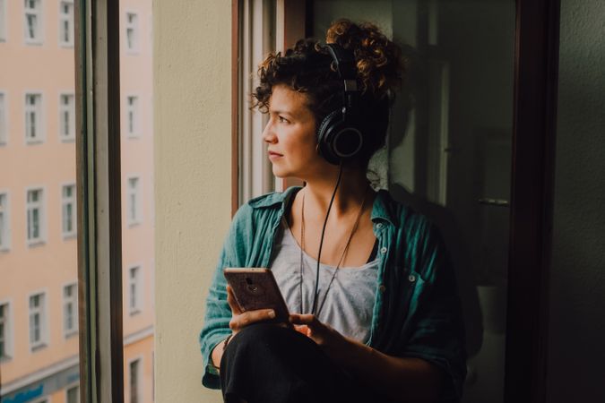 Relaxed woman in headphones using smartphone at home