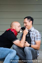 Close up portrait of smiling married couple sitting with their dog in front of their house 4d8xN4