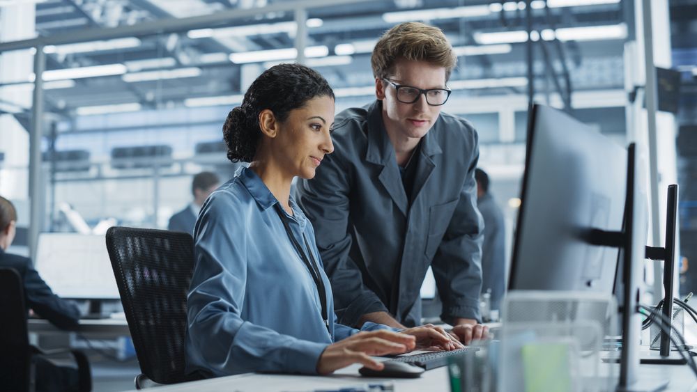 White Man and Hispanic Woman Having Conversation at an Industrial Facility.