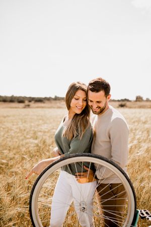 Sincere lovers posing by bicycle on rye field