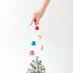 Hand sprinkling baubles on tree