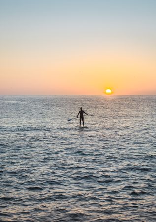 Man practicing paddle surfing with neoprene in a sunrise