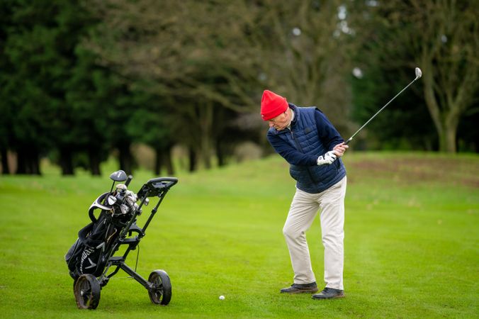 Mature male swinging golf club