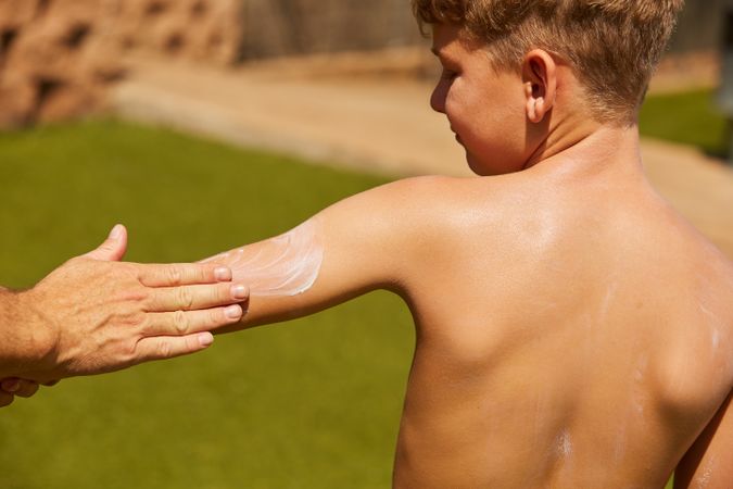 Faceless man applying sun cream on kid