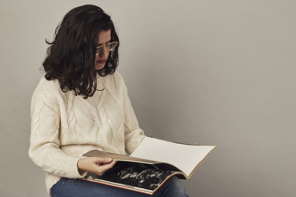 Focused young female looking through book in studio