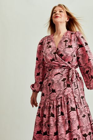 Woman in pink floral dress with long blonde hair in studio