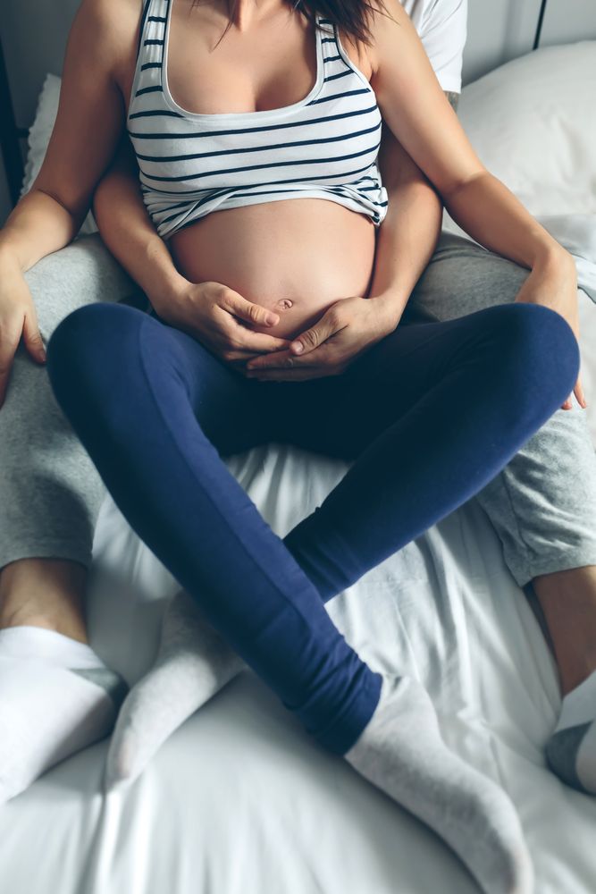 Pregnant woman embraced by her husband
