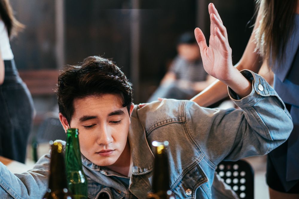 Asian tipsy man sitting at a table in bar