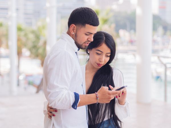 Man messaging on smartphone standing with woman