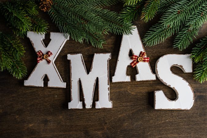 XMAS letters on wooden table surrounded by fir