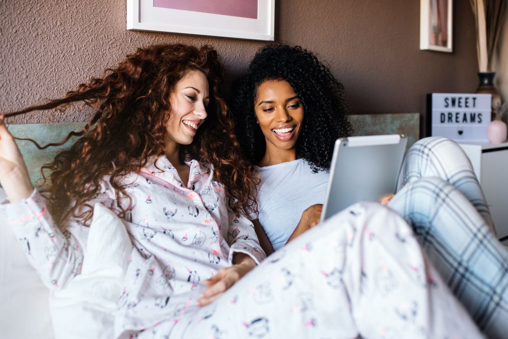 Women in bed entertained on their tablet