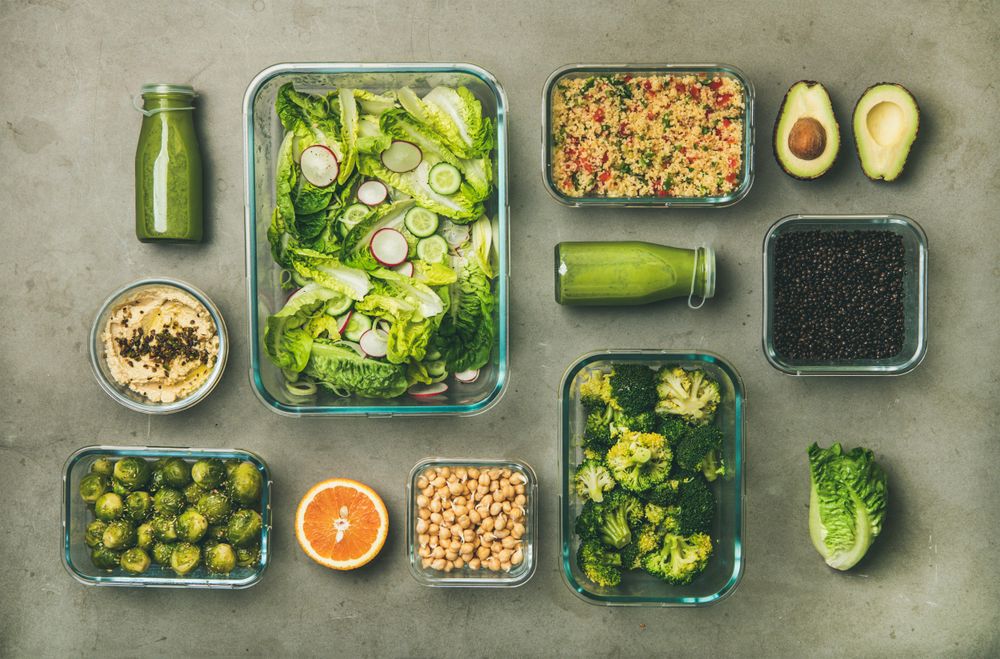 Variety of vegetable dishes arranged in glass containers with bottles of dressing