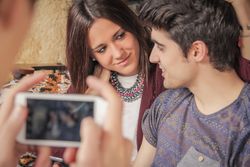 Person hands taking photos to couple on sofa
