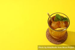 Cold tea with orange slices and mint leaves on a yellow background 5lVXQN