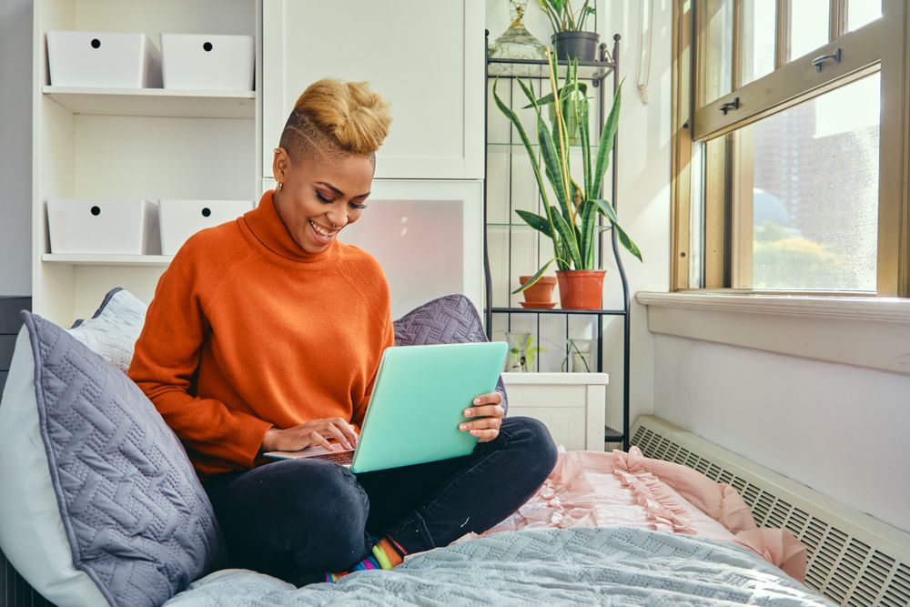 Smiling Black woman with a laptop in a bright modern home