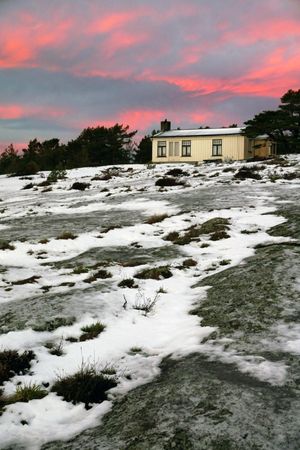 Rural house at snowfield during majestic sunset