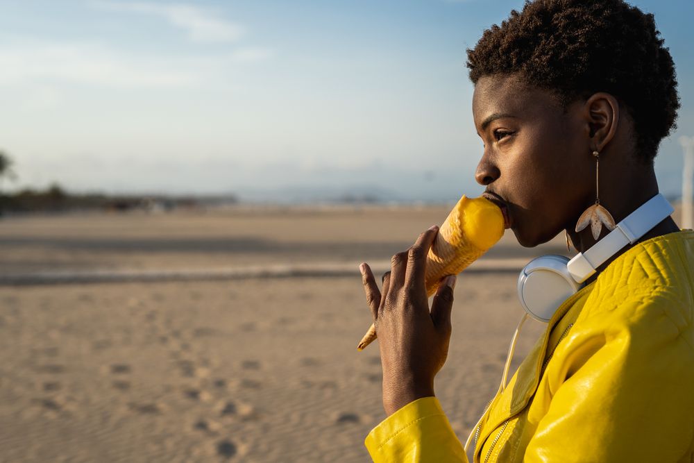 Cool female eating ice cream on beach