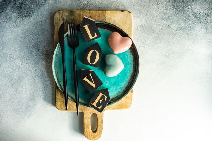 Teal plate with the word "love" and heart decorations on cutting board