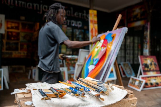 Black artist painting with acrylic paint in studio
