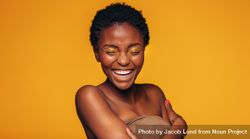 Young woman laughing against yellow background bYPwN4