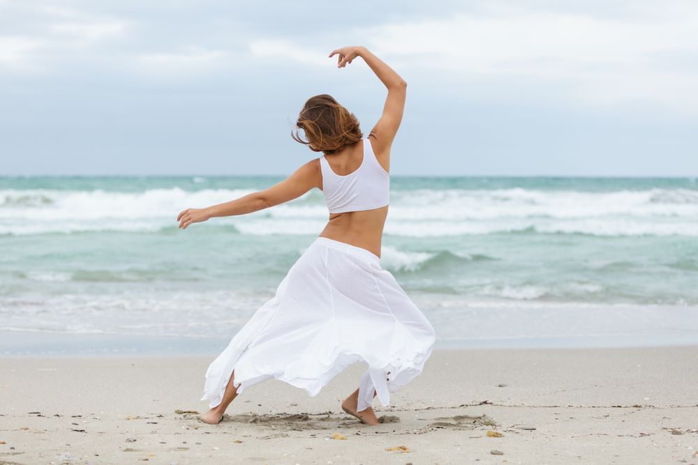 Anonymous woman dancing near sea