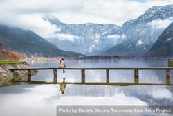 Woman sitting on bridge over beautiful lake with mountains behind 5kMeWb