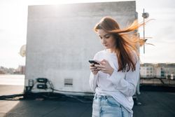 Red haired woman looking down and texting on roof