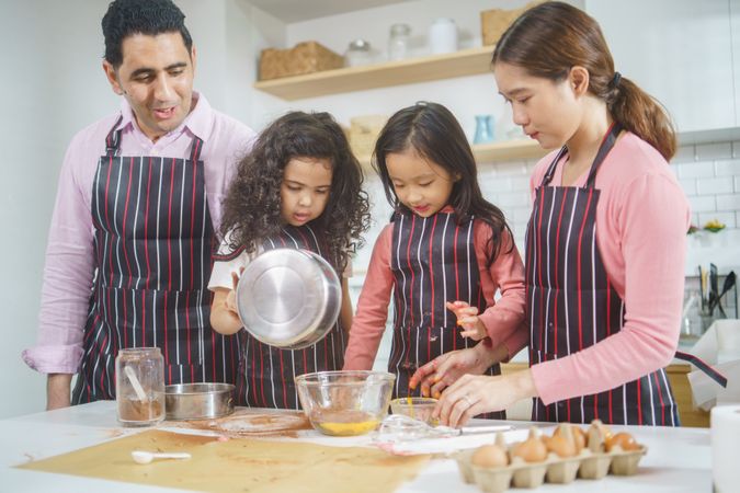 Diverse family mixing baking ingredients together in the kitchen