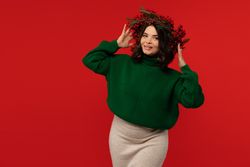 Smiling woman adjusting Christmas wreath of red berries on head.