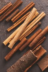 Different sizes of cinnamon sticks on brown background