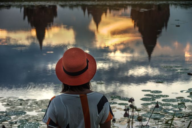 Woman standing at lakeside and enjoying view of Buddhist temples