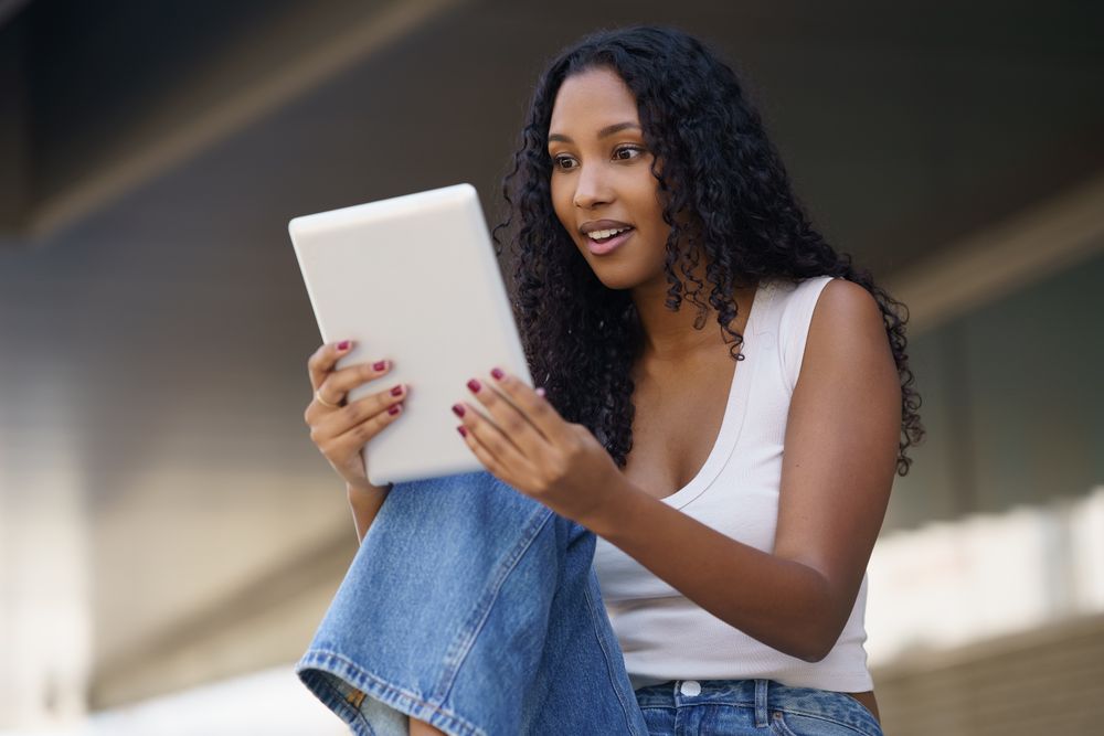 A Young Woman is Actively Engaged with Her Tablet While in a Casual, Relaxed Setting