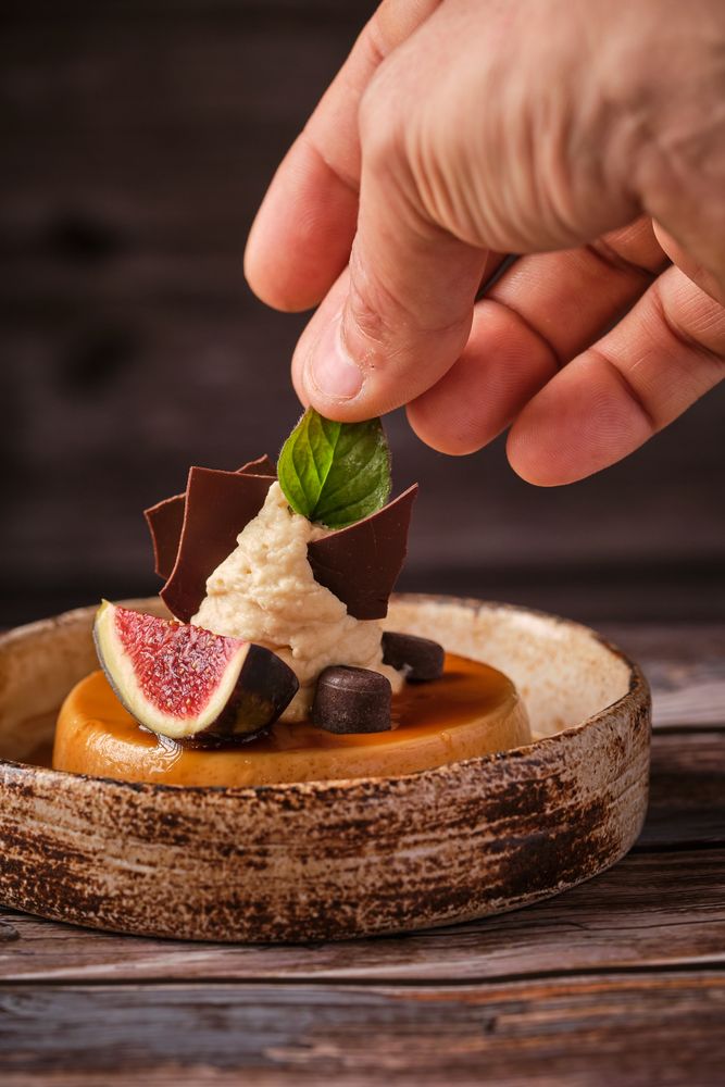 Crop person decorating cake with mint leaf