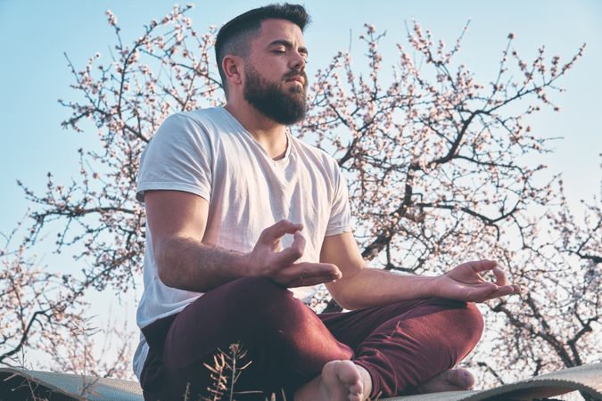 Bearded man meditating in spring garden