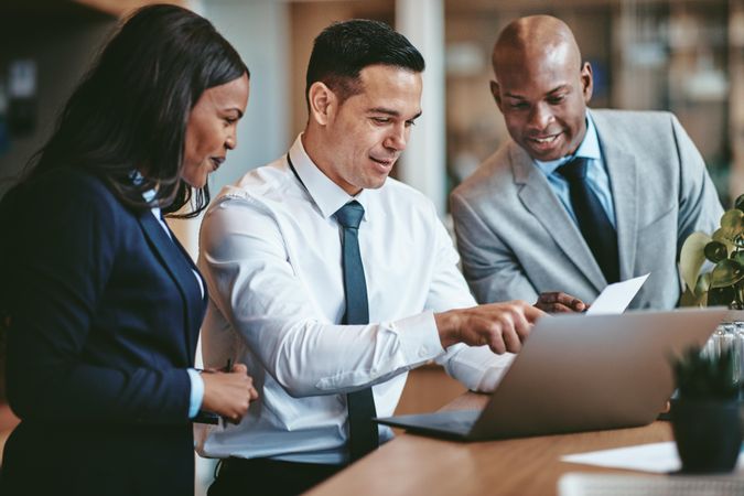 Group of people gathered around a laptop at an office