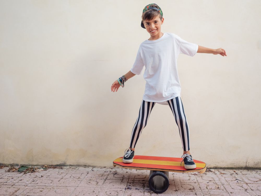 Cheeky boy standing on colorful board and swinging