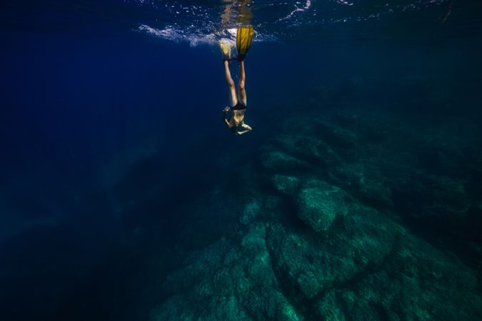 Anonymous young male swimmer diving in blue ocean