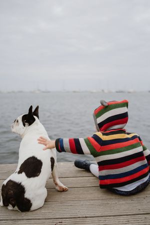 Anonymous kid petting dog on pier