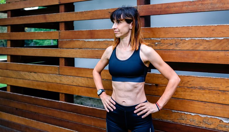 Cheerful female athlete in front of a wooden background