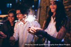 Young friends out at night, celebrating with sparklers 0VYQGb