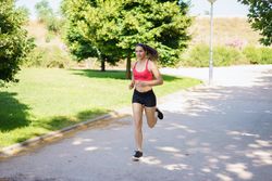 A young woman is jogging in the park, enjoying nature, exercising, and embracing a healthy lifestyle