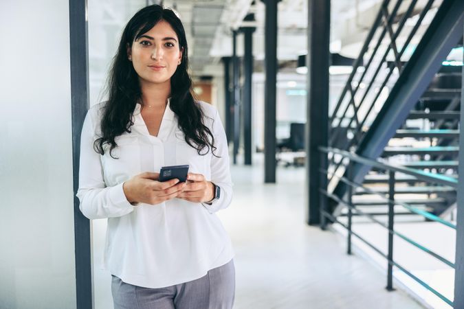 Confident businesswoman holding a smartphone in an office