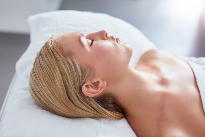 Blonde woman lying back with eyes closed after beauty treatment
