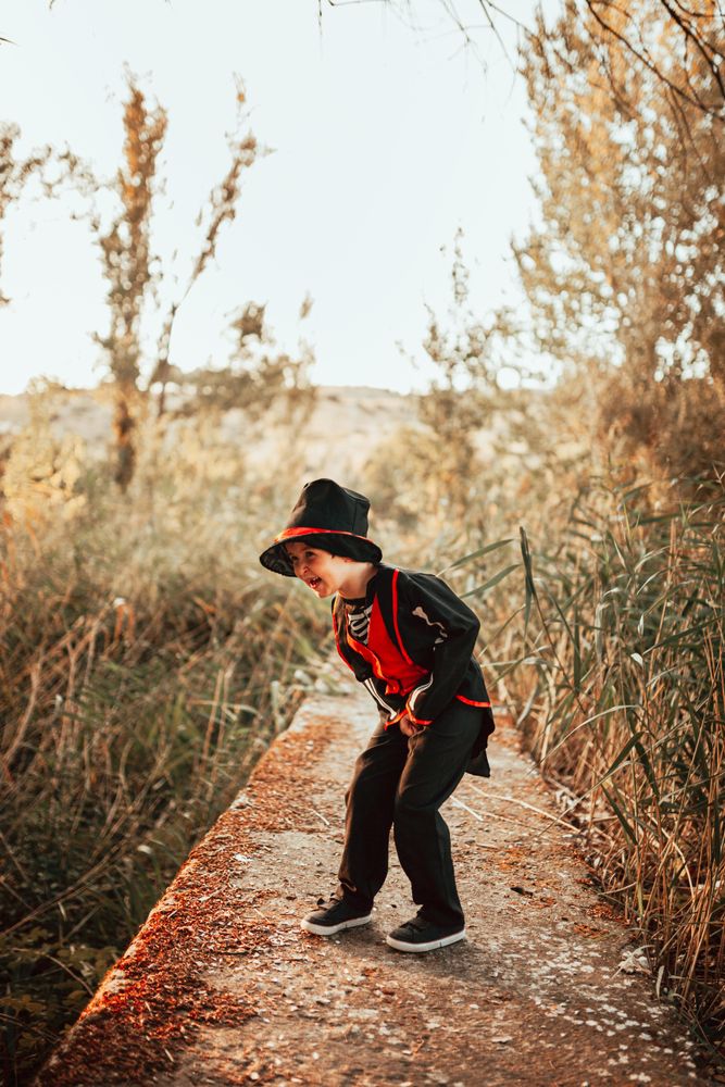 Boy in skeleton costume on a walkway in the forest