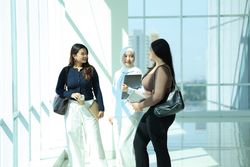 Three Asian Young Colleague Standing at the Big Window, Discussing about Work